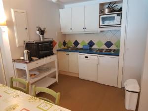 a small kitchen with white cabinets and a microwave at Grand T3 - Terrasse les pieds dans l'eau - Climatisation in Saint-Raphaël