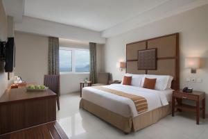 Una habitación de hotel con una cama grande y un escritorio. en Aston Manado Hotel, en Manado