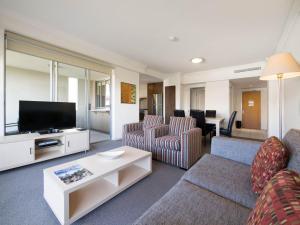 a living room with a couch and a tv at Oaks Brisbane Mews Suites in Brisbane