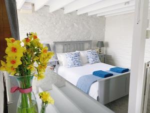 a bedroom with a bed with yellow flowers in a vase at The Laurels Cottages nr Padstow and Wadebridge in Wadebridge