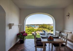 una sala da pranzo con tavolo e vista sull'oceano di Residence Gli Oleandri 140 - Costa Smeralda - Porto Cervo a Liscia di Vacca
