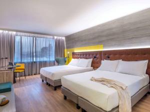 a hotel room with a bed, chair, and nightstand at Pullman Santiago El Bosque in Santiago