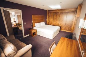 une chambre d'hôtel avec un lit et un canapé dans l'établissement Blackpool Football Club Stadium Hotel, a member of Radisson Individuals, à Blackpool