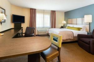 ウィチタにあるMainStay Suites - Wichita NEのベッドとテーブルが備わるホテルルームです。