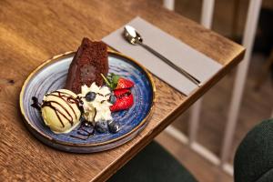 a blue plate with chocolate cake and fruit on a table at Konvin Hotel by Reykjavik Keflavik Airport in Keflavík