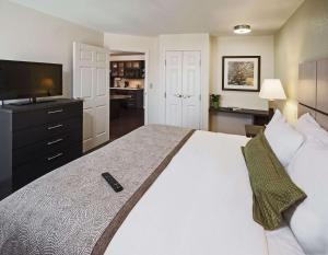 a bedroom with a large white bed with a television at MainStay Suites- Kansas City Overland Park in Overland Park