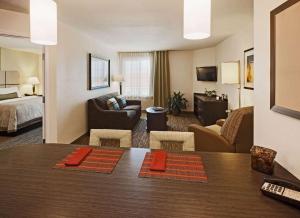 オーバーランド・パークにあるMainStay Suites- Kansas City Overland Parkのベッドとリビングルームが備わるホテルルームです。