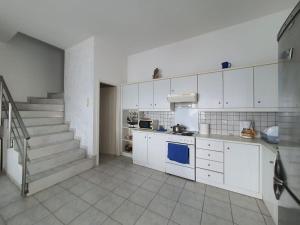 kuchnia z białymi szafkami i schodami w obiekcie Cozy Beach House South Crete w mieście Paránimfoi