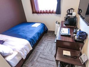 a bedroom with a bed and a desk with a computer at HOTEL LiVEMAX Chiba-Ekimae in Chiba