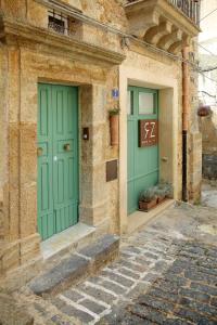 dos puertas verdes en el lateral de un edificio en B&B RONCO ZAFFARANA en Caltagirone