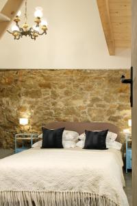 1 dormitorio con 1 cama grande y pared de piedra en B&B RONCO ZAFFARANA en Caltagirone