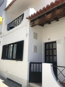 uma casa branca com uma porta preta e janelas em Casa dos Pais em Odeceixe