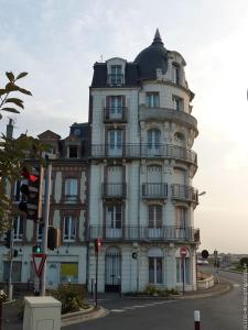 a large white building with a balcony on a street at Escapade de charme les pieds dans l'eau in Houlgate