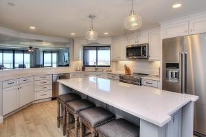 a kitchen with white cabinets and a large island with bar stools at Crescent Beach Club II 9A in Clearwater Beach