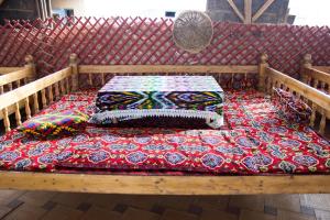 una panca di legno con due cuscini sopra di Kyzylkum Nights Camp & Family Yurt a Nurota