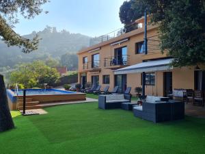 een huis met een tuin met stoelen en een zwembad bij VILLA LA CALA with swimming pool & sea view, 10 min walk from the sea in Blanes
