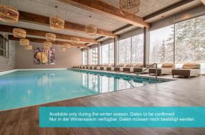 a swimming pool in a building with chairs and windows at Rothornblick 57 by Arosa Holiday in Arosa