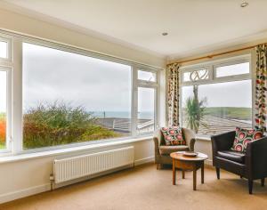 a living room with two chairs and two windows at Sea Mist in Polzeath