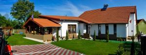 a house with a red roof and a green yard at Pensiunea Narcisa cu Ciubar in Mălăeşti
