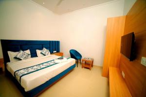 a bedroom with a bed and a chair and a television at Hotel Diamond View in Amritsar
