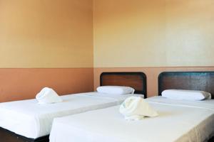 GV Hotel - Ipil في Ipil: سريرين في غرفة ذات أغطية ووسائد بيضاء