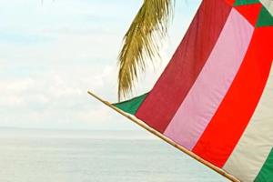 a colorful umbrella on the beach next to a palm tree at GV Hotel - Ipil in Ipil