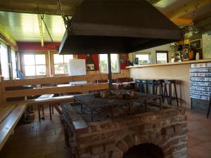 cocina con horno de ladrillo, mesa y bancos en Holiday home OSSA Basecamp, en Sint Odiliënberg