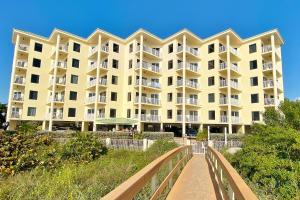 a large yellow apartment building with a walkway at Sunset Vistas Condo 203S in St Pete Beach