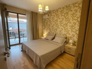 a bedroom with a large bed and a balcony at Sozopol Apartcomplex Onegin 2,free parking in Sozopol