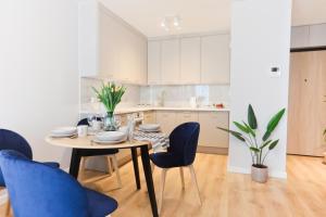 a kitchen and dining room with a table and chairs at M&K Apartamenty Amber Delux, Gdańsk - Wyspa Sobieszewska in Gdańsk