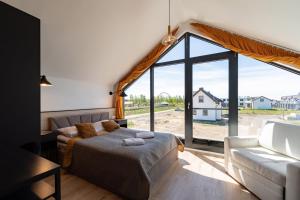 a bedroom with a bed and a couch and a large window at Domki - Bursztynova 13 in Łeba