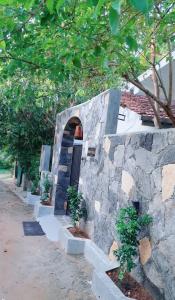 a stone wall with a door and some trees at Dihini Villa in Unawatuna