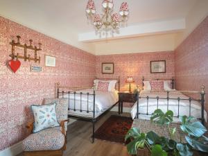 a bedroom with two beds and a chair and a chandelier at Glan Towyn in Holyhead