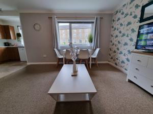 a living room with a table and a television at Swan Path Retreat - 2 Bedroom Apartment in Heybridge