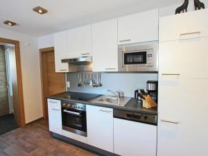 kuchnia z białymi szafkami, zlewem i kuchenką w obiekcie Apartment in See near Ski Slopes w mieście See
