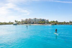 two people on surfboards in a large body of water at Blue Haven Resort- All Inclusive in Grace Bay