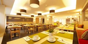 a restaurant with tables and chairs and a cafeteria at Hotel Stachus in Munich