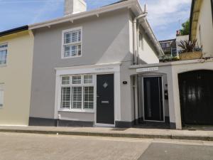a white house with a black door on a street at Harbour Cottage in Torquay