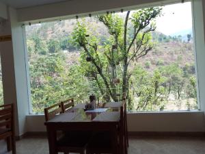 a table and chairs in a room with a large window at Harela Inn in Chamoli