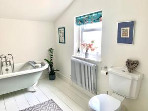 baño con bañera, aseo y ventana en Stunning 3 bed house in the heart of Cheltenham en Cheltenham