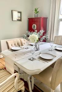 チェルトナムにあるStunning 3 bed house in the heart of Cheltenhamのダイニングルームテーブル(皿、花付)