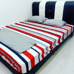 a bed with a red white and blue striped blanket at Homestay Musafir Apartment Seri Iskandar 2.0 in Seri Iskandar