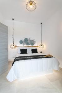 um quarto branco com uma grande cama branca e 2 luzes em Villa Oceana em Mikri Vigla