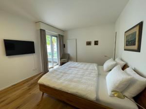 a white bedroom with a bed and a television at Locarno-Monti: Solemonte Apt.103 in Locarno