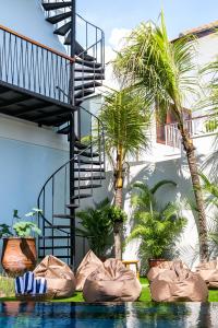 a resort with a swimming pool with palm trees and a staircase at Coco & Pineapple Pants Hostel - CANGGU, BALI in Canggu