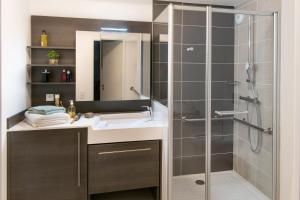 La salle de bains est pourvue d'un lavabo et d'une douche en verre. dans l'établissement DOMITYS La SARDONNE centre-ville, au Puy-en-Velay
