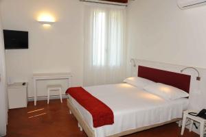 a bedroom with a bed with a red blanket on it at Hotel Albergo al Sole in Malo