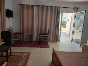 ein Wohnzimmer mit Stühlen und einer Glasschiebetür in der Unterkunft Chambre Hannon Résidence Chahrazad in Sfax