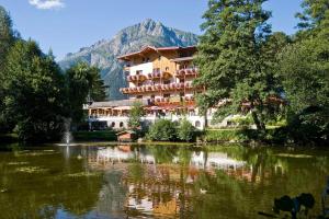 a hotel on a lake with a mountain in the background at Huber Hotel Tramserhof in Landeck