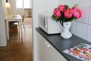 een vaas met roze bloemen op een aanrecht met een magnetron bij Hotell Conrad in Karlskrona